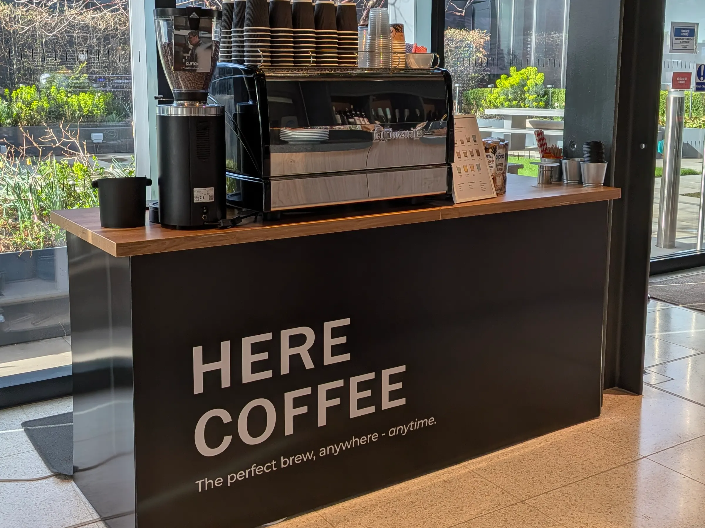 The Here Coffee branded mobile coffee cart set up indoors